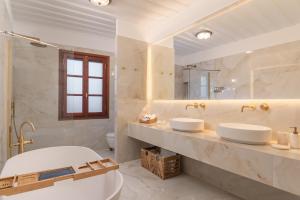 a white bathroom with two sinks and a tub at Keepos by Polykratis in Kokkari