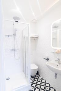 uma casa de banho branca com um chuveiro e um lavatório. em La maison d'Yport em Yport