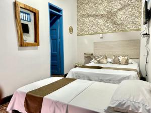 a bedroom with two beds and a blue door at Hotel Kasaya Real in Santa Marta