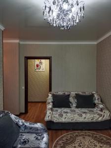 - un salon avec un canapé et un lustre dans l'établissement Квартира, à Astana