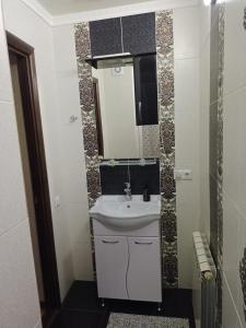 La salle de bains est pourvue d'un lavabo et d'un miroir. dans l'établissement Квартира, à Astana