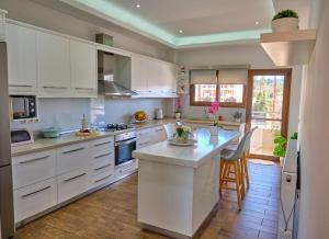 a kitchen with white cabinets and a large island at Elena Luxury Suite Agios Stefanos in Agios Stefanos