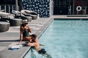 a man and a woman sitting next to a swimming pool at Level Long Beach - East Village in Long Beach