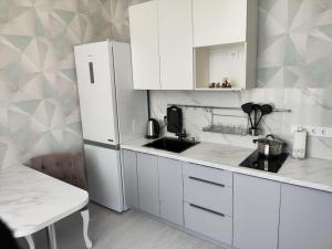 a kitchen with white cabinets and a white refrigerator at ЖК Бухар Жырау in Astana