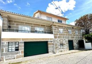 une maison en pierre avec une porte de garage verte dans l'établissement Casa d'Avó Maria - Alojamento rural familiar, à Marco de Canavezes