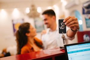 a man holding a key in front of a computer at New Generation Hostel Rome Center in Rome