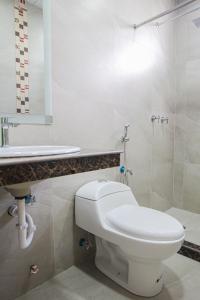 a white bathroom with a toilet and a sink at Hotel Murali - Cerca del Aeropuerto de Guayaquil in Guayaquil