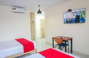 a bedroom with a bed and a desk and a tv at Hotel Murali - Cerca del Aeropuerto de Guayaquil in Guayaquil