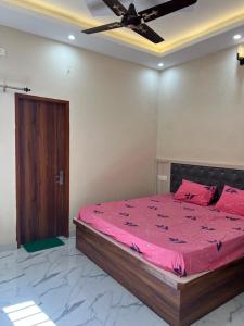 a bedroom with a bed with pink sheets and a ceiling at Spacious Villa in Dehradun in Dehradun