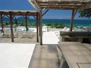 une terrasse avec une table et des chaises et l'océan dans l'établissement Suites em Juquei, à Juqueí