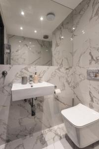 a white bathroom with a sink and a toilet at Luxury Georgian House in Marylebone: Modern 1-Bed Retreat in London