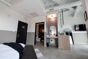 a bedroom with a bed and a sink and a mirror at Arch + Cable Hotel in Mankato