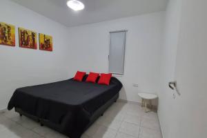 Schlafzimmer mit einem schwarzen Bett und roten Kissen in der Unterkunft Casa familiar de 2 dormitorios in Neuquén