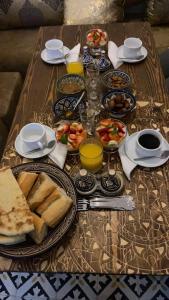 een tafel met borden en glazen sinaasappelsap bij Riad D’AR GANne by Carole in Essaouira