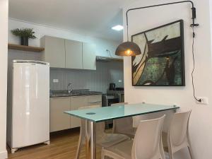 cocina con mesa, sillas y nevera en Beira Mar Apartmento 107 en Maceió
