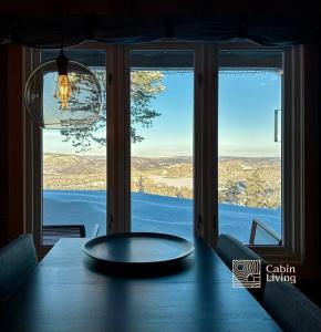 a dining room table with a view of a window at Cozy cabin with incredible views and sauna in Lampeland