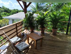 une terrasse en bois avec un banc et des palmiers dans l'établissement Villa-Coco, à Grand-Bourg