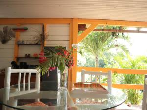 un tavolo di vetro con un vaso di fiori su un portico di Villa-Coco a Grand-Bourg