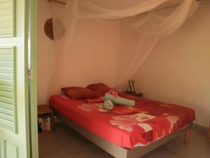 a bedroom with a bed with a red comforter at Villa-Coco in Grand-Bourg