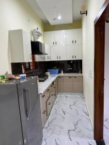 a kitchen with white cabinets and a marble floor at Spacious Villa in Dehradun in Dehradun