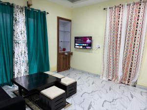 a living room with green curtains and a black table at Spacious Villa in Dehradun in Dehradun