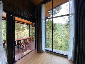 a room with large windows and a dining room with a table at บ้านเคียงธาร โฮมสเตย์ แม่แมะ Cascade Lodge Homestay in Amphoe Chiang Dao