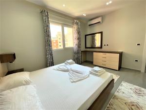 a bedroom with a white bed with towels on it at Vlora Apartment in Vlorë