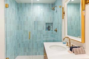 Baño de azulejos azules con lavabo y espejo en Sycamore Villa II, en Los Ángeles