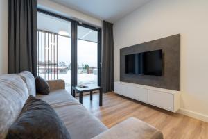 uma sala de estar com um sofá e uma televisão de ecrã plano em Apartament Laguna Beskidów 8 z widokiem na Jezioro Żywieckie - Dream Apart em Zarzecze