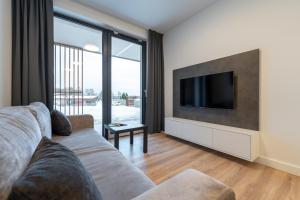 a living room with a couch and a flat screen tv at Apartament Laguna Beskidów 8 z widokiem na Jezioro Żywieckie - Dream Apart in Zarzecze