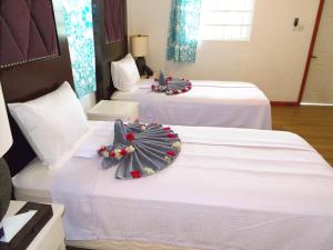 Basil At Villa في Arnos Vale: سريرين في غرفة فندق بعرصي عليهم