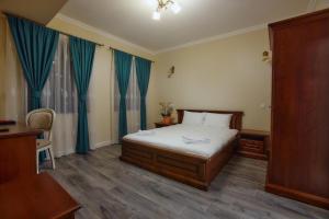 Schlafzimmer mit einem Bett mit blauen Vorhängen in der Unterkunft Hotel Restaurant Imperium in Botiz