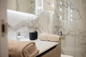 ein Bad mit einem Waschbecken, einer Dusche und Handtüchern in der Unterkunft Suits recién reformadas Marqués de Vadillo in Madrid