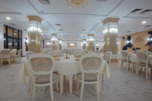 uma sala de jantar com mesas e cadeiras brancas em Hotel Restaurant Imperium em Botiz