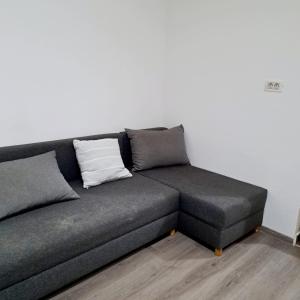 a gray couch with two pillows on a white wall at Apartament spatios - zona UTA in Arad