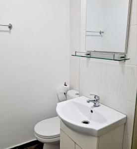 a white bathroom with a toilet and a sink at Apartament spatios - zona UTA in Arad