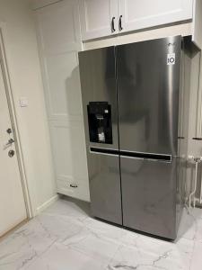 a stainless steel refrigerator in a kitchen with white cabinets at Härligt stort boende i perfekt läge in Borås