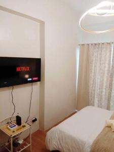 1 dormitorio con 1 cama y TV en la pared en The Loop North Tower en Cagayán de Oro