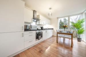 una cucina con armadi bianchi e tavolo in legno di 2 Bed Flat in Brentford with Parking a Brentford