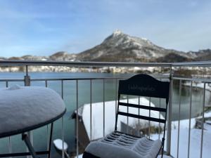 uma cadeira sentada numa varanda com neve em Brunnwirt ESSEN & WOHNEN em Fuschl am See