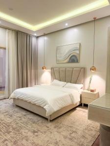 a bedroom with a large white bed and a table at شقة مودرن مقابلة البوليفارد in Riyadh