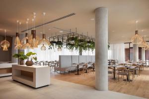 Hotel Materra في أوسييك: غرفة طعام بها طاولات وكراسي وثريات