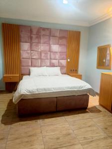 sypialnia z dużym łóżkiem z różowym zagłówkiem w obiekcie Home to home luxury apartments and suites w mieście Benin