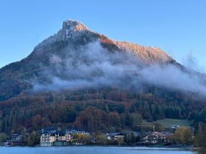 a mountain with a house in front of a lake at Brunnwirt ESSEN & WOHNEN in Fuschl am See