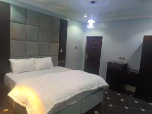 sypialnia z dużym białym łóżkiem i żyrandolem w obiekcie Home to home luxury apartments and suites w mieście Benin
