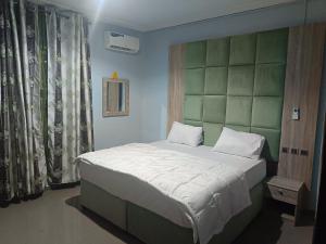 - une chambre avec un grand lit et une tête de lit verte dans l'établissement Home to home luxury apartments and suites, à Benin City
