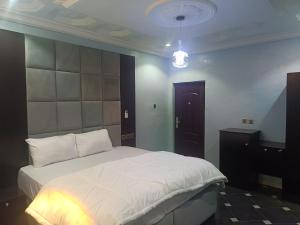 - une chambre avec un grand lit blanc dans l'établissement Home to home luxury apartments and suites, à Benin City