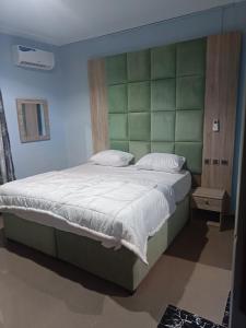 una camera con un grande letto con testiera verde di Home to home luxury apartments and suites a Benin City