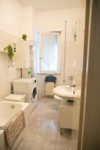 a white bathroom with a sink and a washing machine at Discover Sustainable Bliss: 2-BR Apartment in Rome in Rome