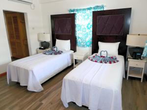 two beds in a room with white walls and wood floors at Basil At Villa in Arnos Vale